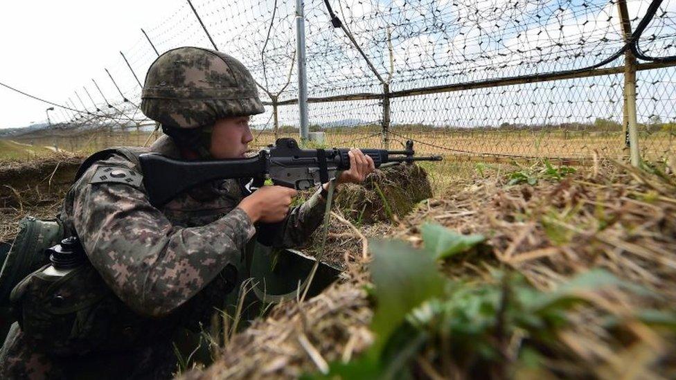 A South Korean soldier stands guard in front of a military fence at a General Outpost (GOP) of the Demilitarized Zone dividing the two Koreas in Cheorwon on October 13, 2015.