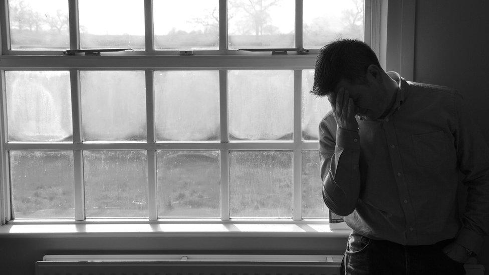 Man by a window with his head in his hand