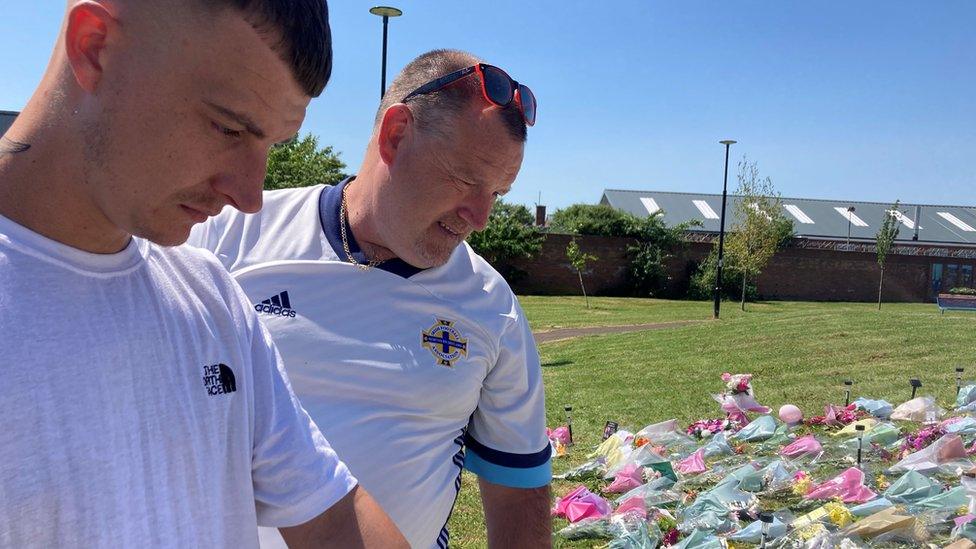 Chloe Mitchell's brother and uncle viewing floral tributes ahead of the vigil in Ballymena