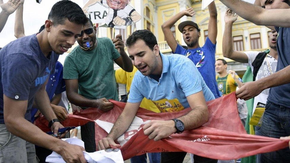 Protesters in Belo Horizonte tear a flag of the governing Workers' Party (13 March)