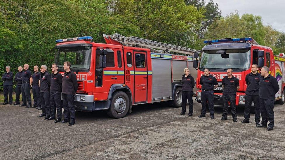 Fire crews stand in front of engine