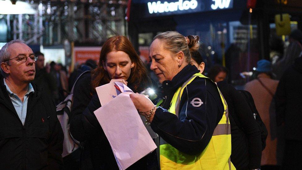 A TfL staff member directing commuters