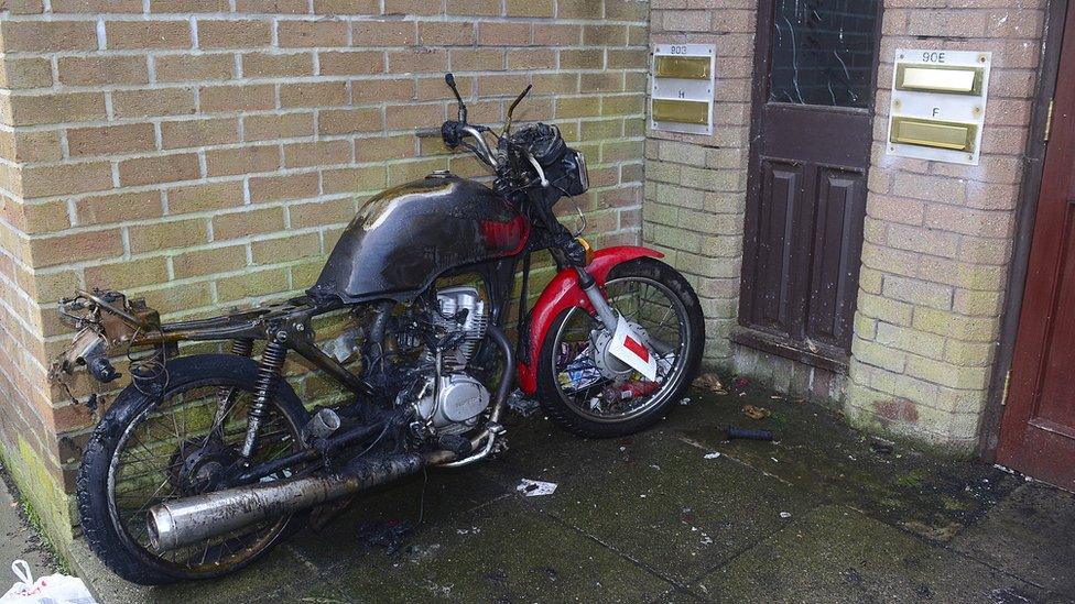 A charred motorbike that was set on fire outside the flats