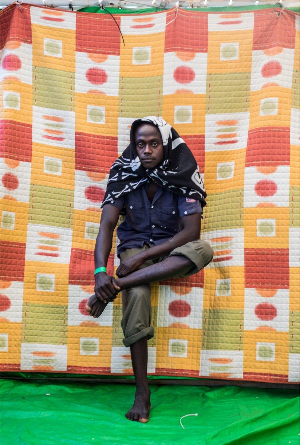 Ibrahim Mohammed poses for the camera with a blanket wrapped around his head