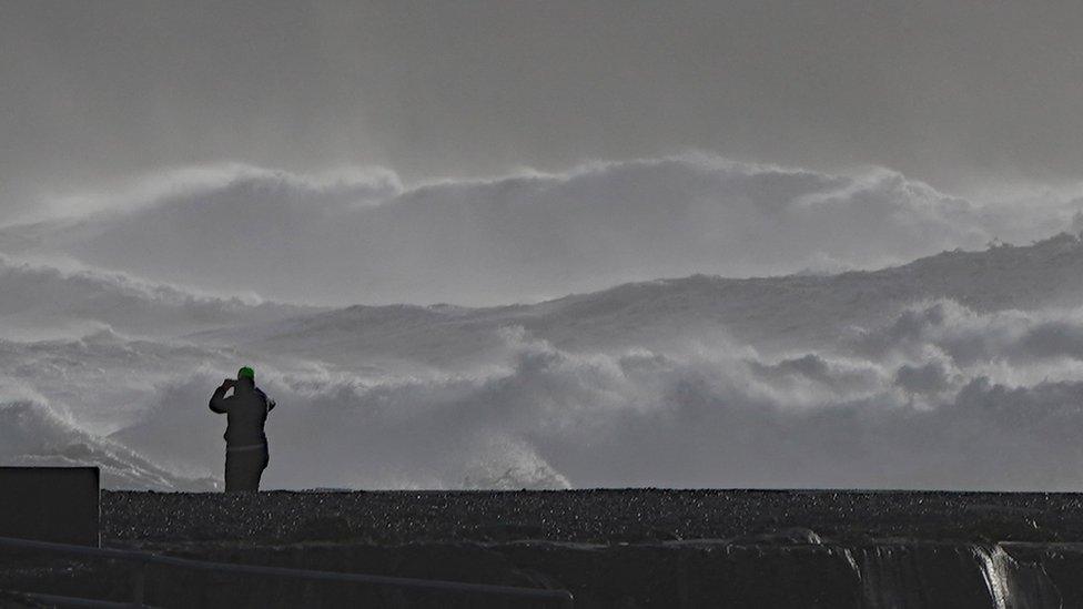 A person photographs high waves in Doolin in County Clare on the west coast of Ireland.