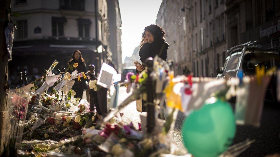 A person cries as she stands at a makeshift memorial for a tribute to the victims of a series of deadly attacks in Paris, in front of the Casa Nostra restaurant in Paris on November 23, 2015