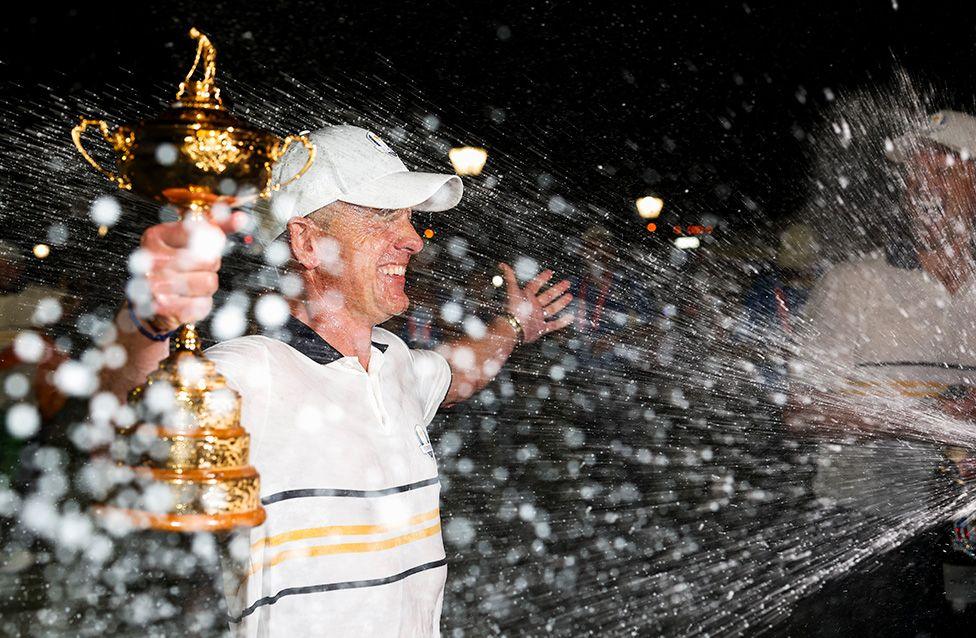 Captain Luke Donald holds the Ryder Cup trophy as he is doused with champagne celebrating Europe defeating the United States. Photo by Richard Heathcote