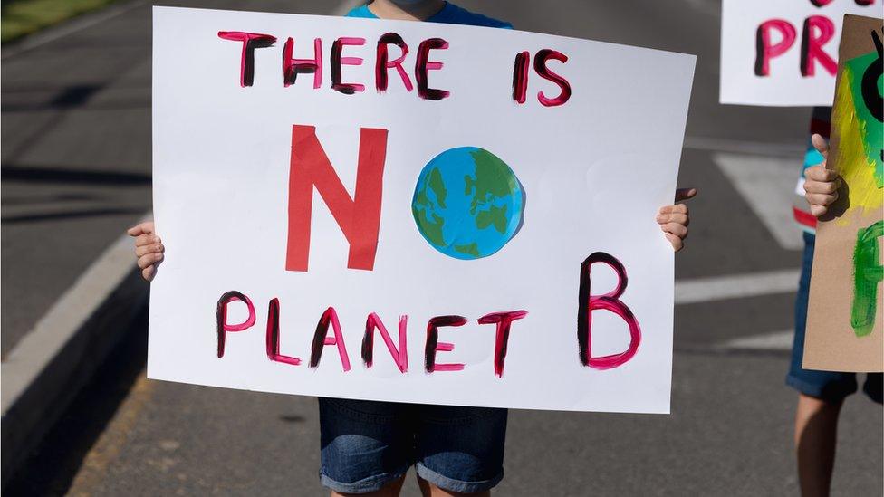 child holding a sign saying there is no planet B