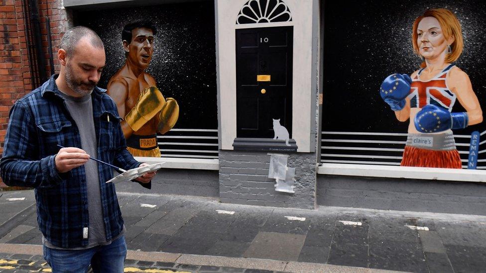 Artist Ciaran Gallagher paints Larry the cat onto a mural in Belfast city centre