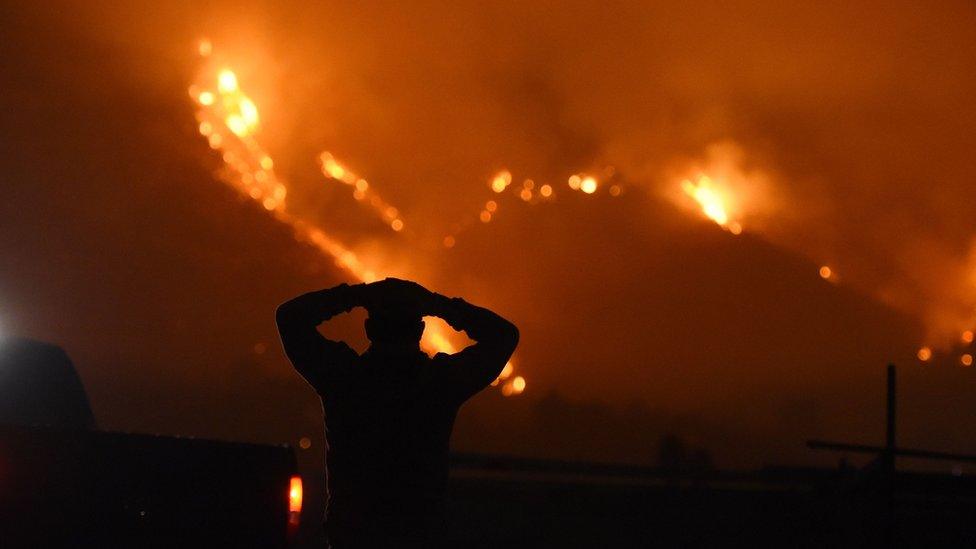 Man stands watching the fire burn