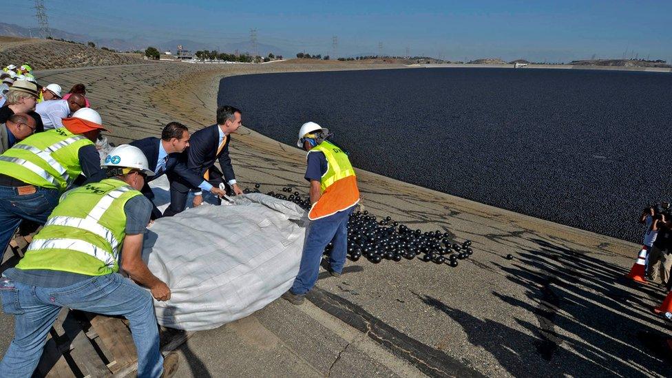 Workers release plastic 'shade balls' into a reservoir in Los Angeles