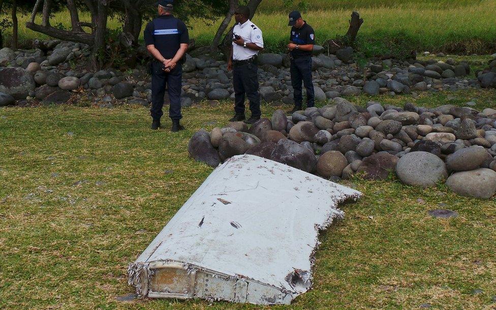 French gendarmes and police stand near a large piece of plane debris that washed up on the island of Reunion