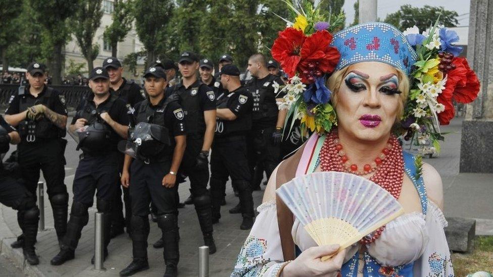 A drag queen poses in front of police