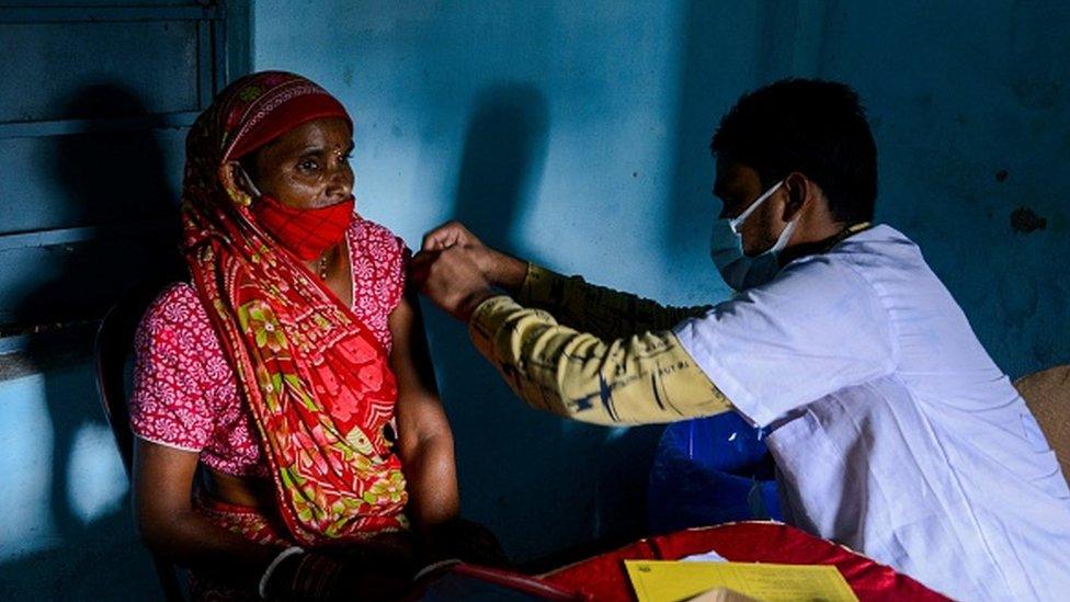 A health worker inoculates a woman with the dose of Covishield