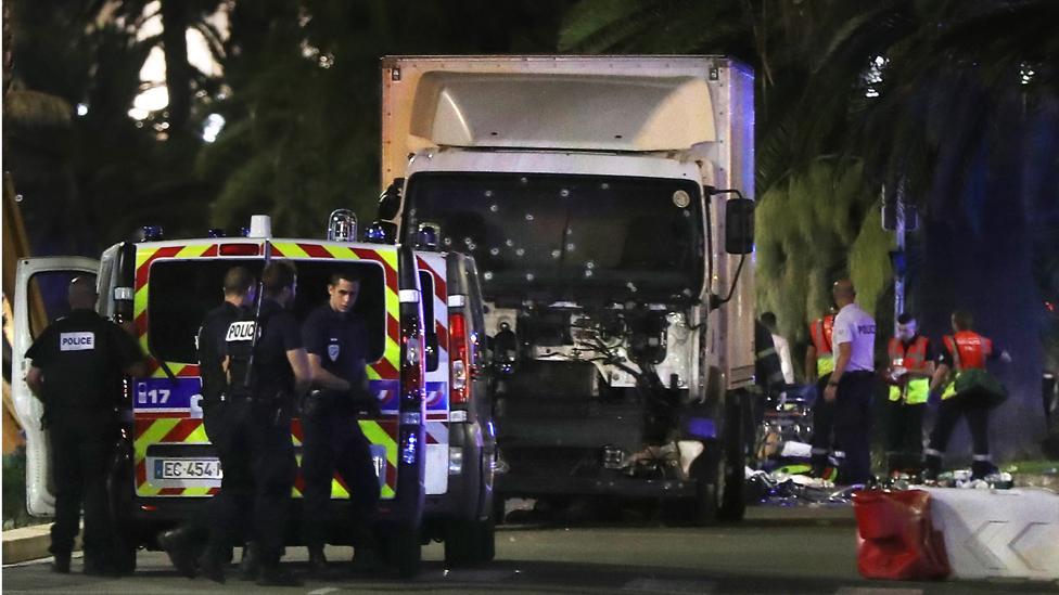 Police officers and rescue workers stand near a van that ploughed into a crowd leaving a fireworks display in the French Riviera town of Nice on July 14, 2016.