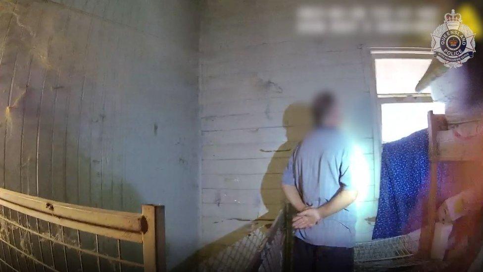 Man in blue shirt and shorts standing in a derelict room