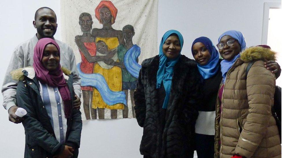 Dirar family standing in front of a portrait