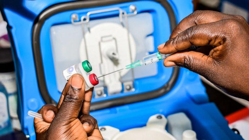 A health worker measures the dosage of malaria vaccine