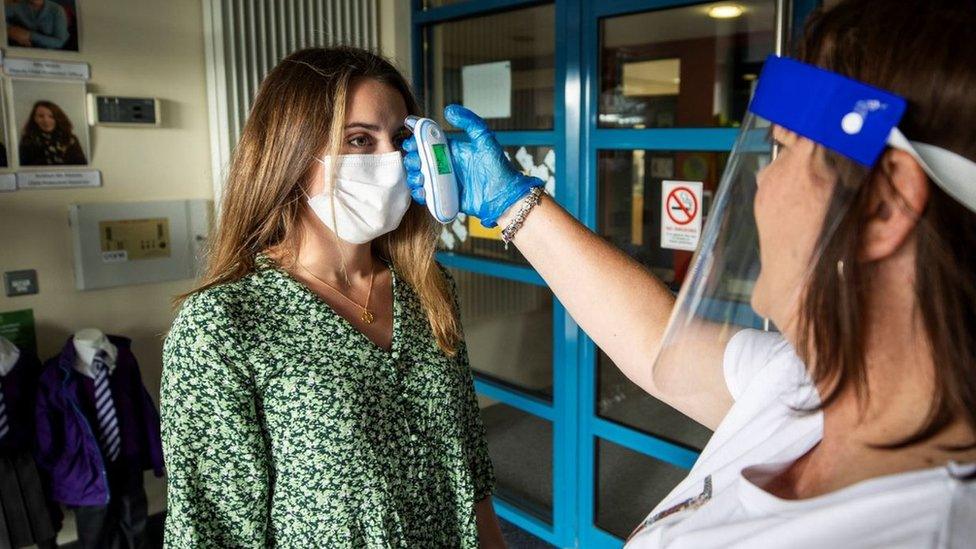 Teacher Catherine McClean has her temperature checked by assistant teacher Hilary Brennan at St Clare's Primary School in Belfast at the start of the new term