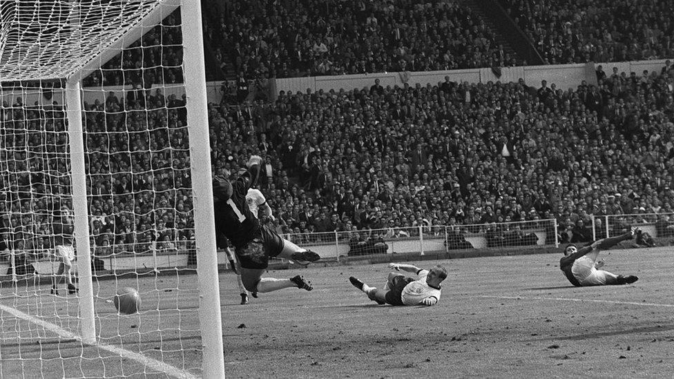 Geoff Hurst scoring England's controversial third goal as West Germany goalkeeper Hans Tilkowski dives for the ball during the World Cup Final on 30 July, 1966