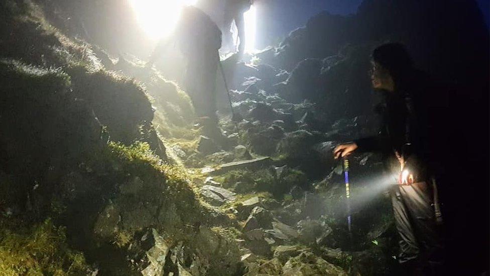 Rescuers walk down steep stone path