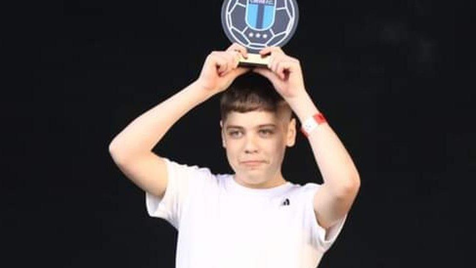 Kane receiving a football trophy