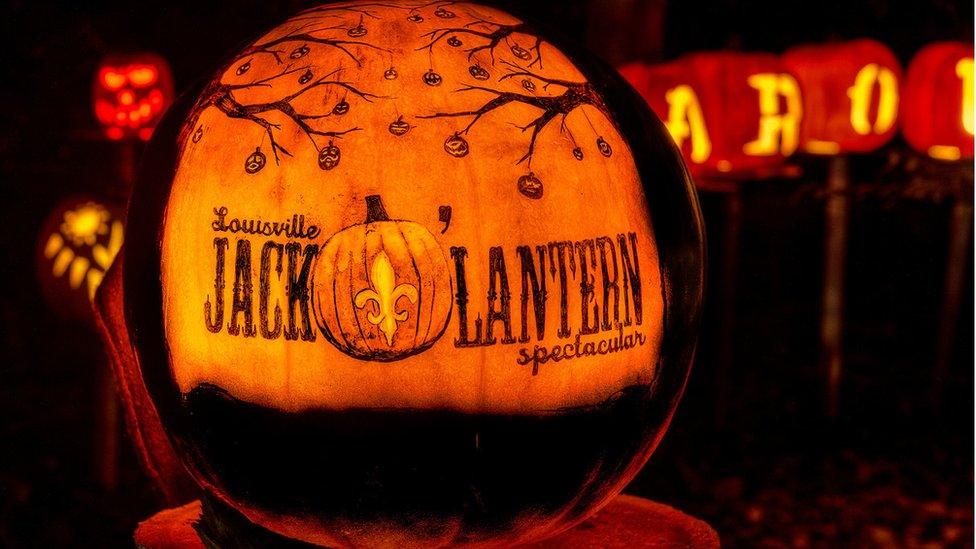 A Jack-O'-Lantern glows orange with the words 'Louisville Jack-O'-Lantern spectacular' carved into its side.