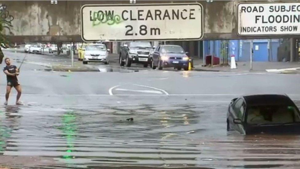 Paris Diaz Jordanou pretends to fish near a floating car in Melbourne