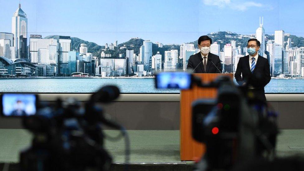 TV news cameras film Hong Kong's Secretary for Security John Lee Ka-chiu speaking during a press conference, May 2021