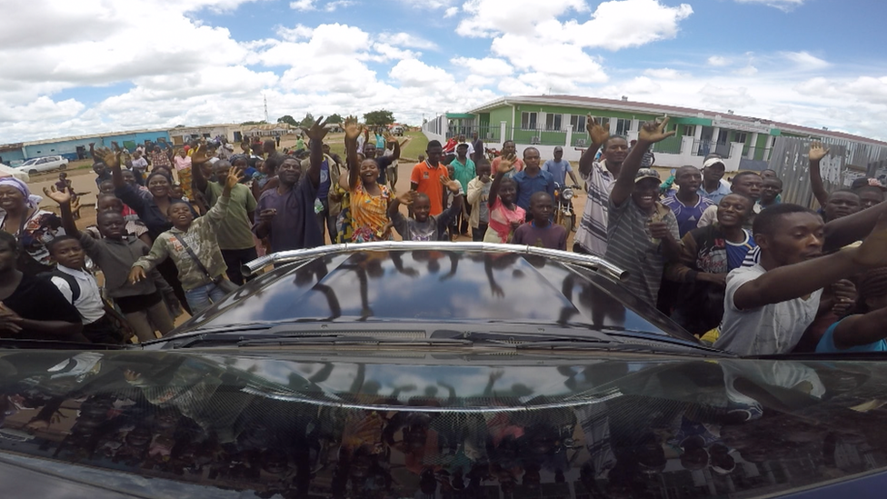 People crowd around car