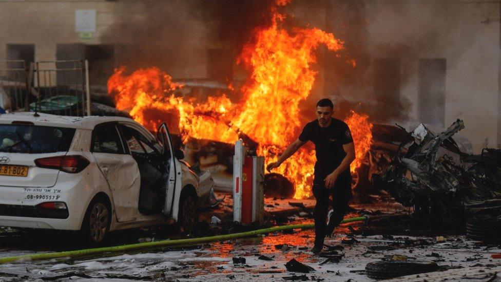 A man runs on a road as fire burns after rockets were launched from the Gaza Strip, in Ashkelon, Israel October 7, 2023.