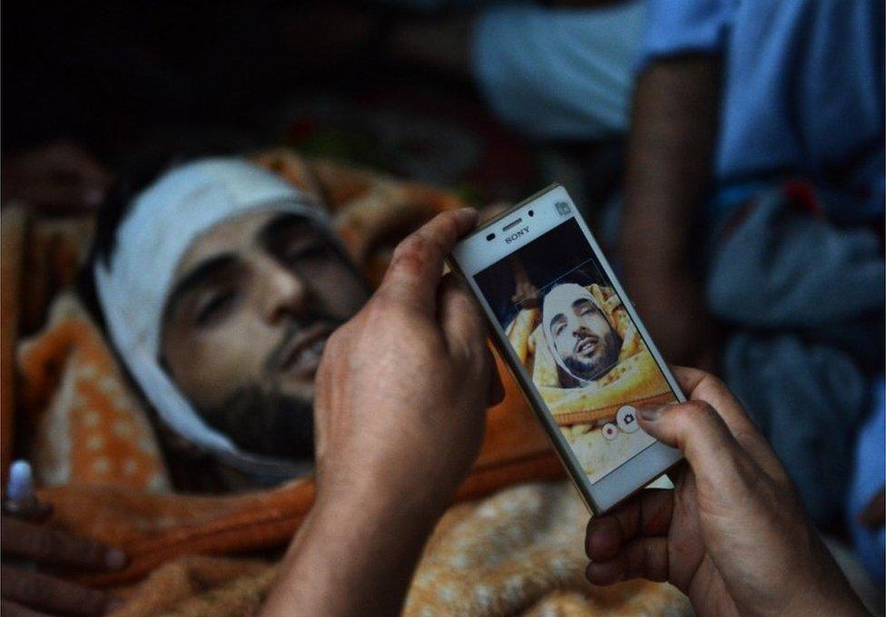 In this photograph taken on July 9, 2016, Kashmiri mourners take photographs of the body of Burhan Muzaffar Wani, the new-age poster boy for the rebel movement in the restive Himalayan state of Jammu and Kashmir, ahead of his funeral in Tral, his native town, 42kms south of Srinagar.