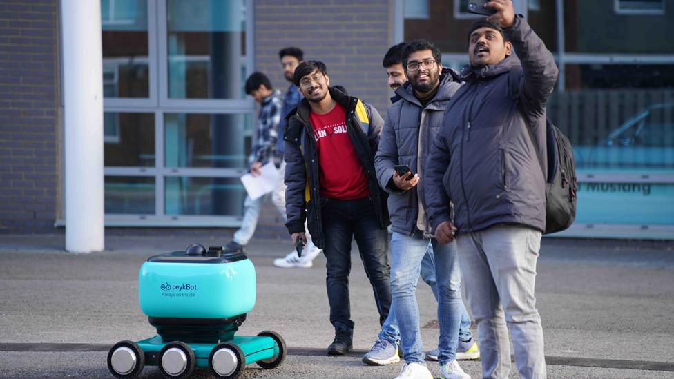 Students standing by a robot and taking a selfie