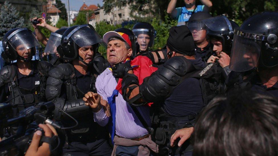 Police grab a protester in Romania