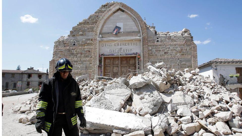 A firefighter walks past the remains of a church Villa San Lorenzo, near Amatrice, central Italy, Saturday, 27 August 2016