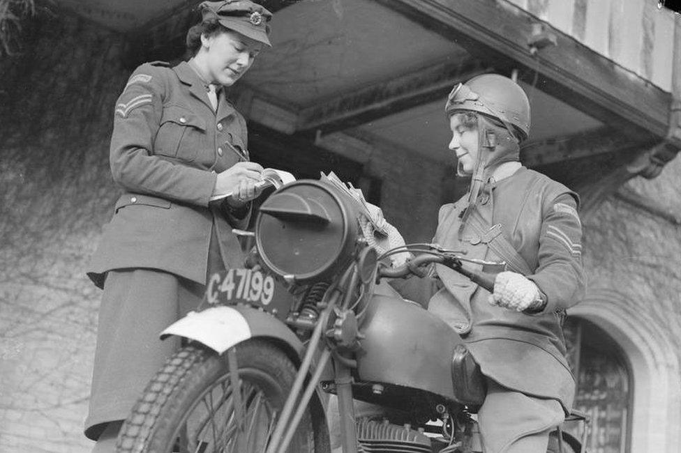 An ATS FANY Motorcycle Messenger sits on her motorbike as she receives her instructions from a FANY Corporal at the ATS MTC training centre, Camberley. © IWM (D 5721)