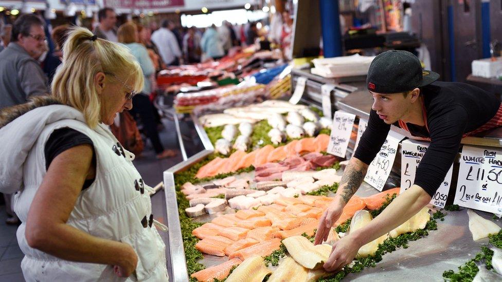 A woman buys fish from a stall