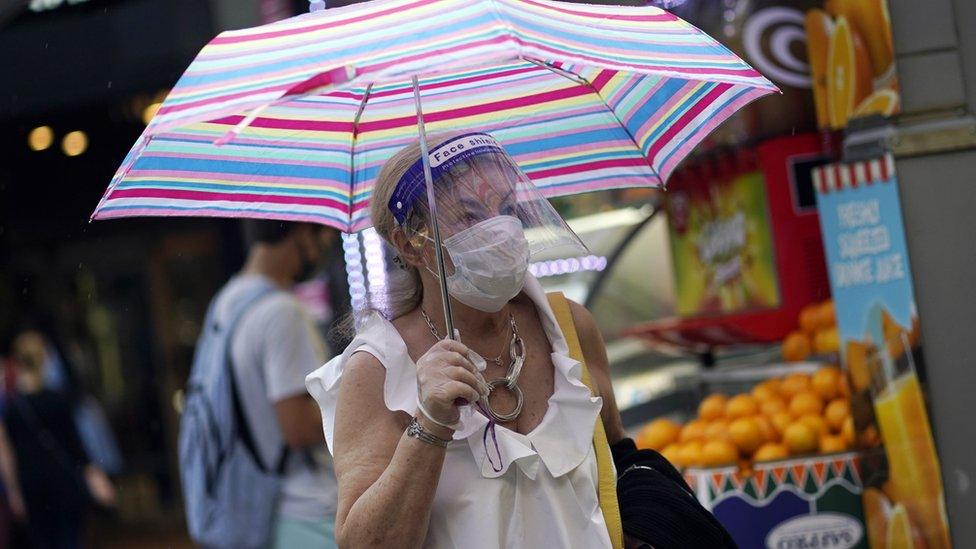 A woman shields from rain on Oxford Street in London