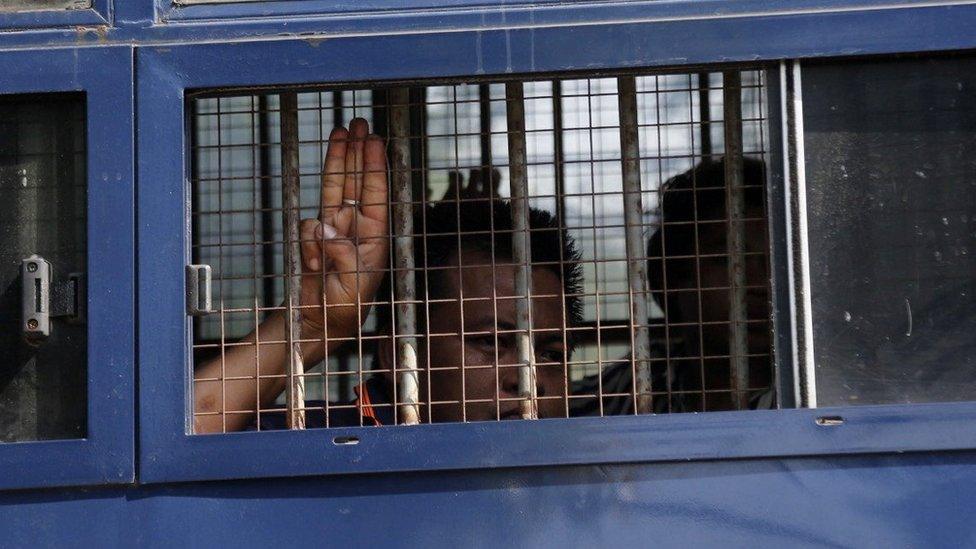 A man flashes the three-finger salute after being arrested during a protest against the military coup in Mawlamyine, Myanmar, 12 February 2021