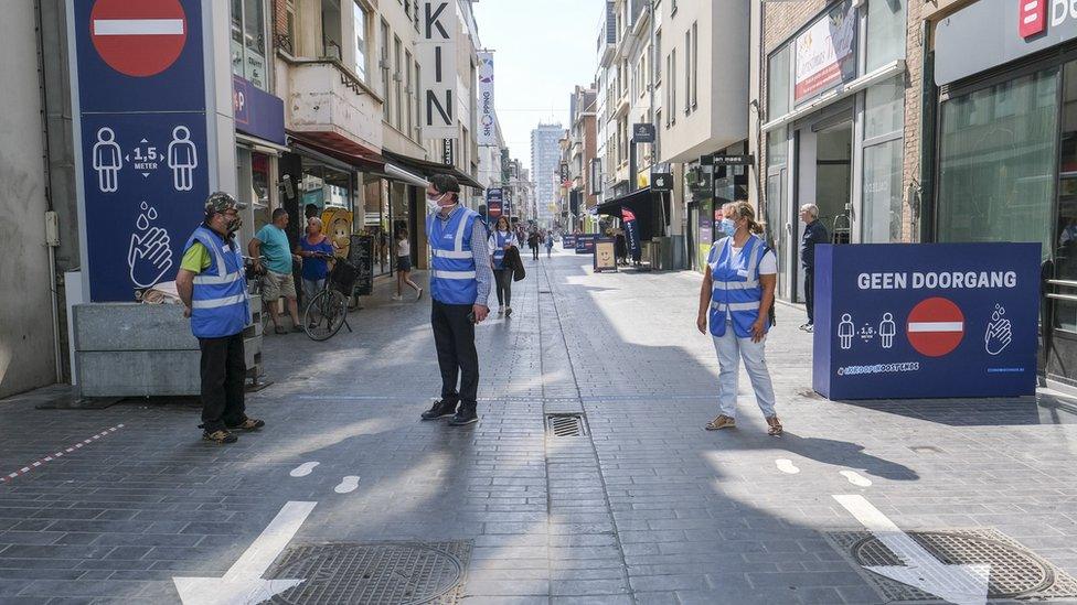 Stewards wearing face masks enforce a one-way system for pedestrians in Ostend, Belgium (21 May 2020)