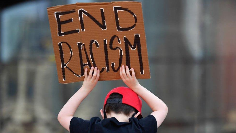 A child hold an 'end racism' sign