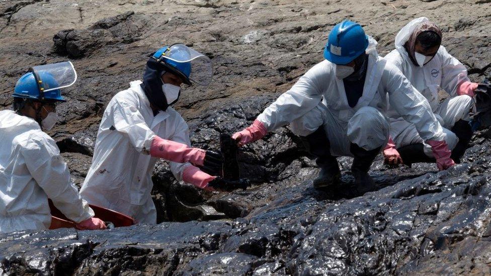 Cleaning crews work to remove oil from a Peruvian beach