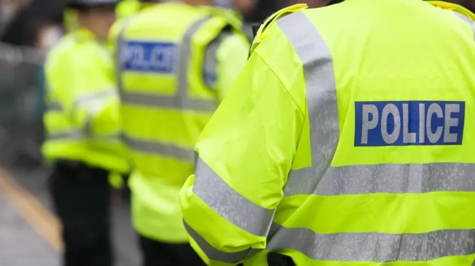 The back of a police officer, wearing a fluorescent police coat with police written on the back