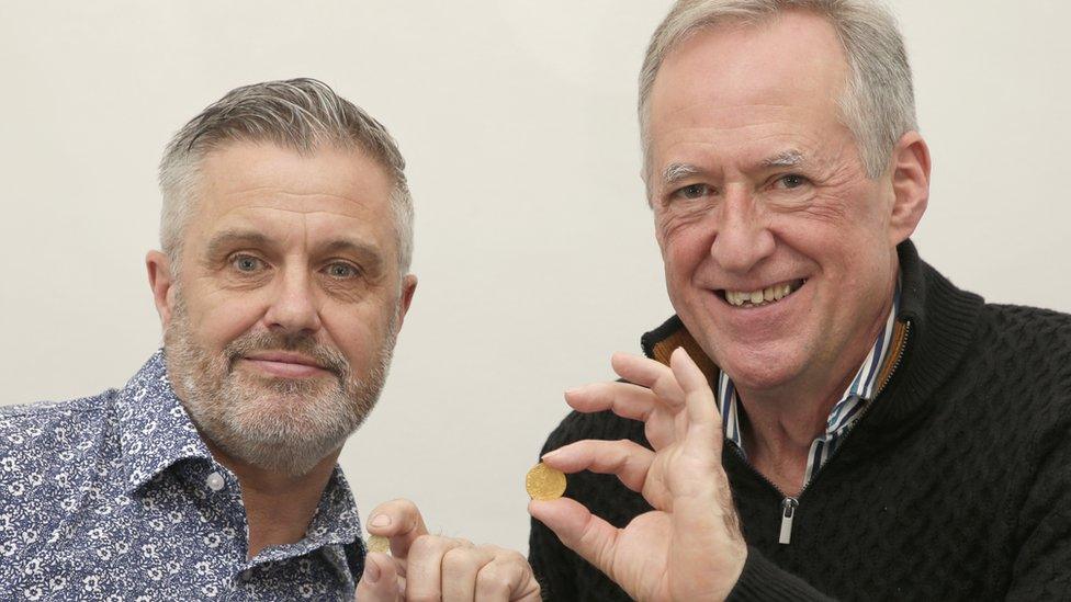 Metal detectorists Mark Pallett and Andy Carter, both holding up a gold coin each