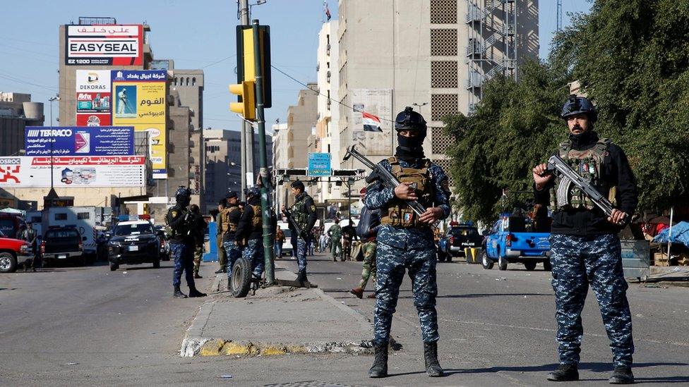 Iraqi security forces stand near the scene of a twin suicide bomb attack in Baghdad on 21 January 2021