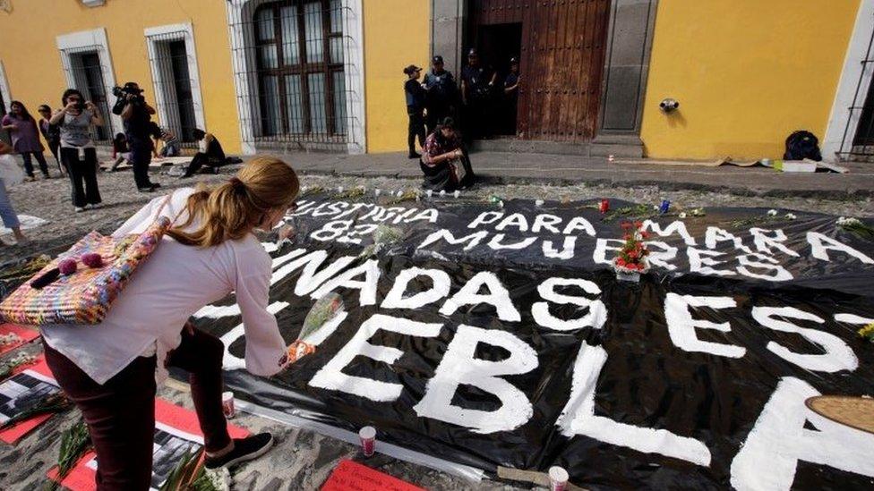 A woman places flowers during a vigil in Puebla. The sign reads "Justice for Mara" and "Women killed in Puebla". (17/09/2017)