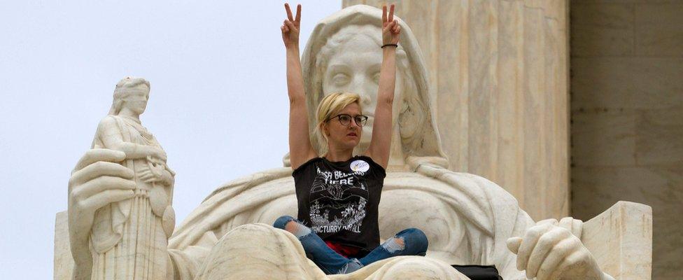 Demonstrator Jessica Campbell-Swanson of Denver, sits on the lap of the "Contemplation of Justice" statue