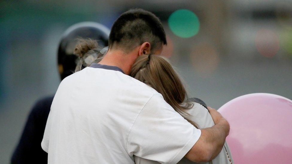 A man embraces a woman and a teenager