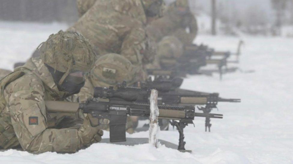 Soldiers lying down shooting rifles in the snow