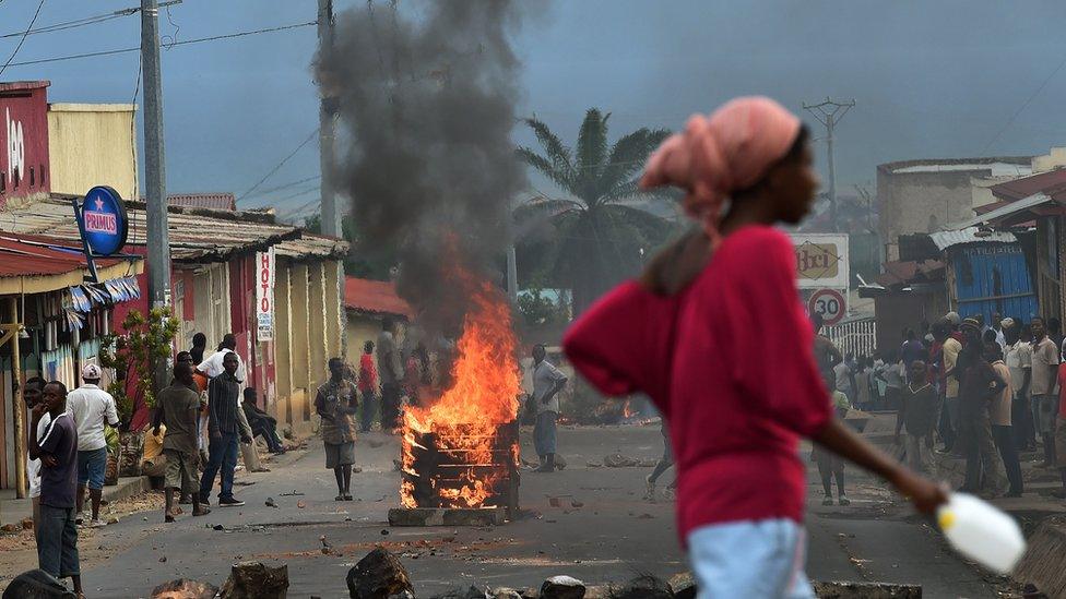 A woman walks past a burning barricade during a demonstration against in Bujumbura, Burundi -May 2015